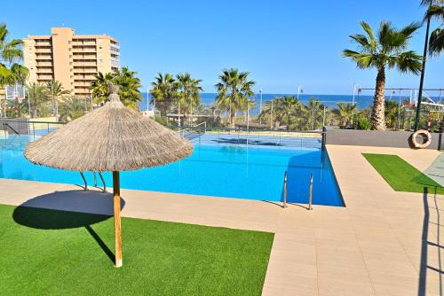 ein Strohschirm neben einem Swimmingpool in der Unterkunft Myflats Luxury Sea Coast in Arenales del Sol