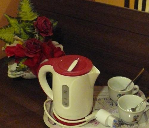 a tea kettle with a red top on a table with two cups at Hotel Leone in Rome