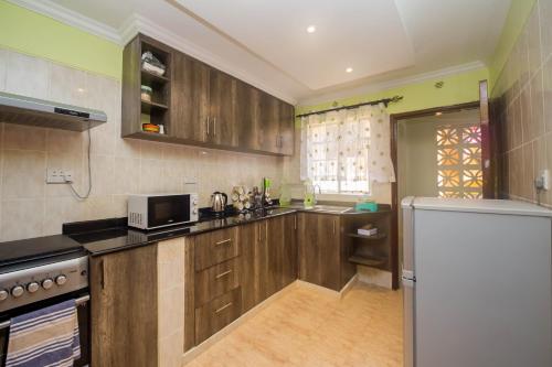 uma cozinha com armários de madeira e um frigorífico branco em Esterina Suites em Nairobi