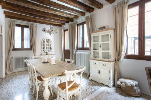 a dining room with a wooden table and some windows at Romantic Rialto in Venice