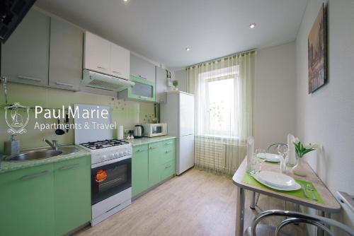 a kitchen with green and white cabinets and a table at PaulMarie Apartments on Shahterov in Salihorsk