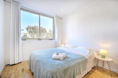 une chambre blanche avec un lit et une fenêtre dans l'établissement Cannes Heart of town Cozy bright warm & sunny studio by Olam Properties, à Cannes