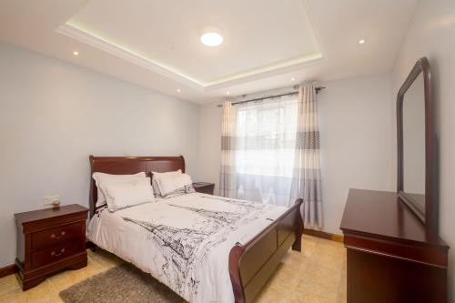 a bedroom with a bed and a dresser and a window at Esterina Suites in Nairobi