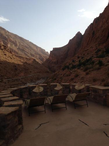 a group of chairs and umbrellas in a canyon at Auberge Le Festival Todra Gorge in Aït Baha