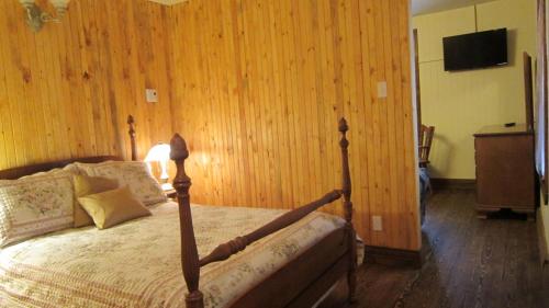 a bedroom with a bed with a wooden wall at Auberge Le Four à Pain in Petite-Rivière-Saint-François