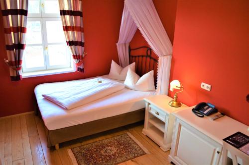 a bedroom with a bed with red walls and a window at Die Kronacher Stadthotels in Kronach
