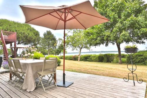 une table avec un parasol sur une terrasse dans l'établissement Rêves de bord de mer, à Locmariaquer