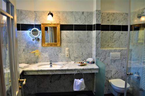 a bathroom with a sink and a toilet and a mirror at Die Kronacher Stadthotels in Kronach