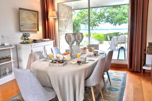 jadalnia ze stołem z krzesłami i oknem w obiekcie Rêves de bord de mer w mieście Locmariaquer