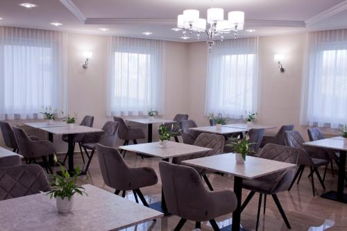 a dining room with tables and chairs and windows at Relax Panzió in Győr