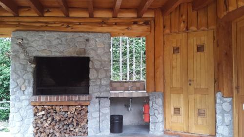 an outdoor kitchen with a stone fireplace and a sink at El Raulí del Bonito in Villa La Angostura