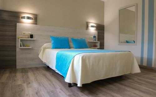 a bedroom with a large bed with blue pillows at Hostal Restaurante el Cary in Montemayor
