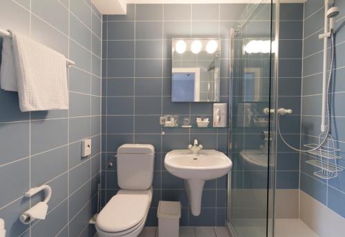 een blauw betegelde badkamer met een toilet en een wastafel bij Hotel Kavaliershaus/Schloss Bad Zwesten in Bad Zwesten