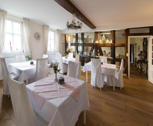 Hotel Kavaliershaus/Schloss Bad Zwesten في باد سفيستِن: غرفة طعام مع طاولات بيضاء وكراسي بيضاء