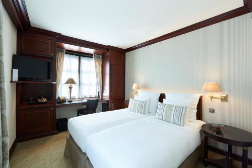 a hotel room with a large white bed and a desk at Warwick Grand-Place Brussels in Brussels
