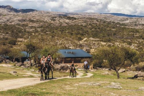 a group of people riding horses in front of a cabin at Los Ancares Resort in Mina Clavero