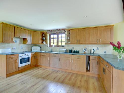 a large kitchen with wooden cabinets and wooden floors at Holiday Home Travenna by Interhome in Saint Mawgan