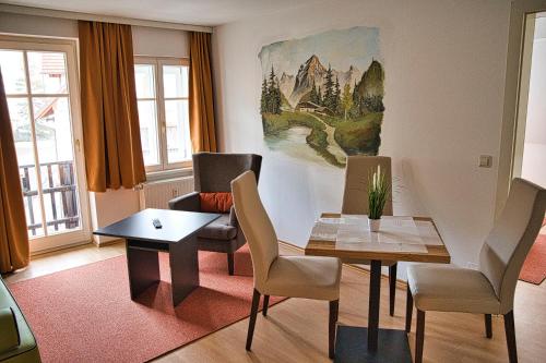 a living room with a table and chairs and a painting at GRASSEGGER APPARTEMENTHAUS in Sankt Johann am Tauern