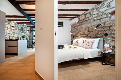a bedroom with a brick wall and a white bed at Dal Pescatore in Rovinj