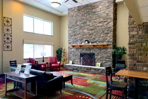 a living room with a stone fireplace and chairs at AmericInn by Wyndham Wausau in Weston