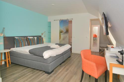 een slaapkamer met een bed, een bureau en een stoel bij Hotel Brasserie Brakzand in Schiermonnikoog