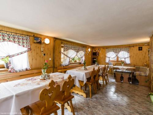 - une salle à manger avec des tables, des chaises et des fenêtres dans l'établissement Nad Grapą, à Gliczarów