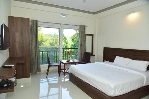 a bedroom with a bed and a desk and a window at Grand Misty Heaven in Madikeri