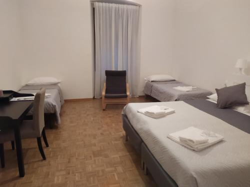 a hotel room with two beds and a desk and a table at Affittacamere Iris in Trieste
