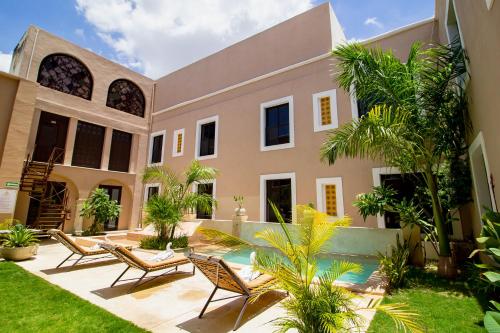 una casa con un patio con sillas y árboles en Hotel Merida, en Mérida
