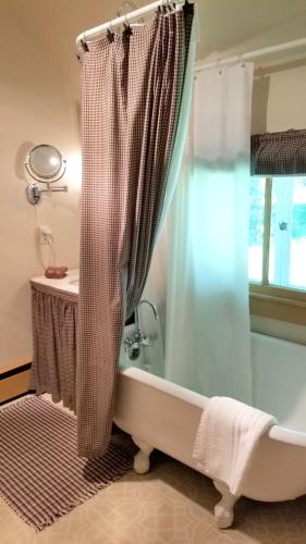 a bathroom with a tub and a shower curtain at Timbercliffe Cottage Inn in Camden