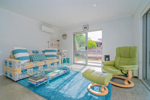 een woonkamer met een bank en een stoel bij Rose's Beach Pad - Matarangi Holiday Home in Matarangi