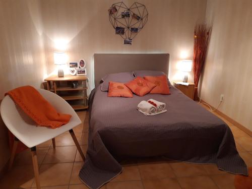 um quarto com uma cama com almofadas laranja e uma cadeira em La Meïzou, gîte - chambres d hôtes à Champeix em Champeix