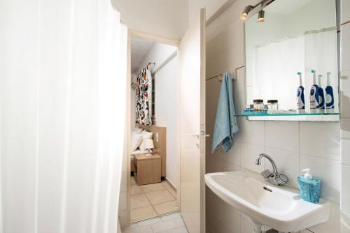 a white bathroom with a sink and a mirror at Castello Apartments in Stalida