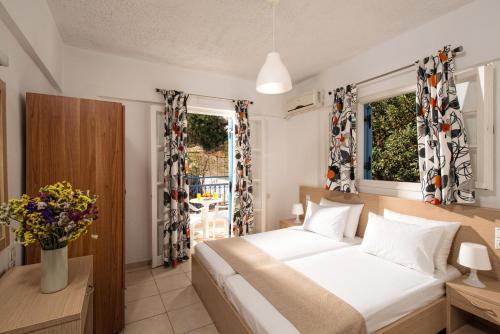 a bedroom with a white bed and two windows at Castello Apartments in Stalís