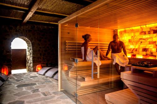 Un uomo e una donna seduti in una sauna di Dammusi Al-Qubba Wellness & Resort a Pantelleria