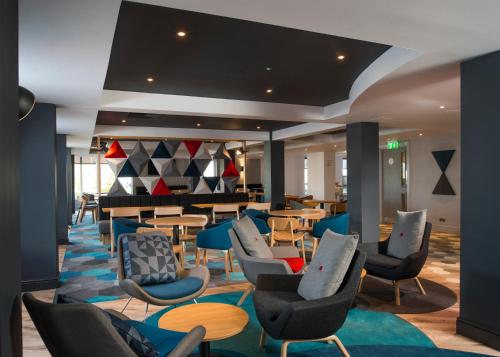 a lobby of a hotel with chairs and tables at Holiday Inn Express Edinburgh - Leith Waterfront, an IHG Hotel in Edinburgh