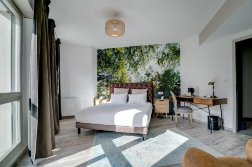 a bedroom with a bed and a table and a desk at La Maison Hôtel Mulhouse Centre in Mulhouse