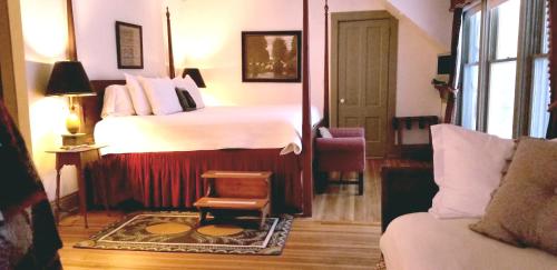 a bedroom with a large bed and a chair in it at Timbercliffe Cottage Inn in Camden