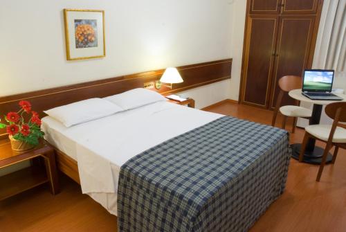 une chambre d'hôtel avec un lit et un ordinateur portable sur une table dans l'établissement Crillon Palace Hotel, à Londrina