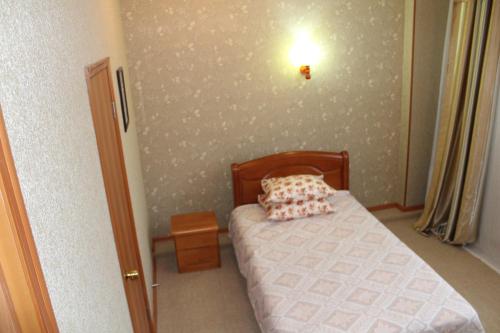 a small bedroom with a bed and a light on the wall at Ayhan Hotel in Aktobe