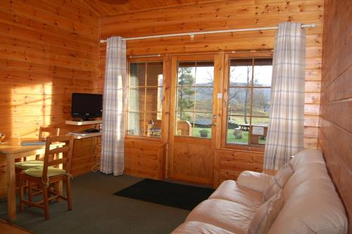 sala de estar con sofá y escritorio en Cosy Rowan woodland lodge no3 en Killin