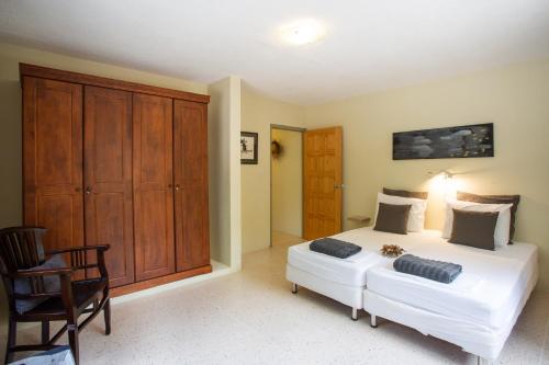 a bedroom with a large white bed and a chair at B&B Sombre di Kabana in Willemstad