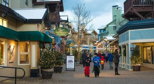 a group of people walking down a street with christmas trees at The Black Bear Lodge at Stratton Mountain Resort in Stratton Mountain