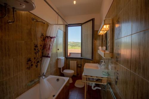 bagno con lavandino, servizi igienici e finestra. di AZ.AGR.POGGIO REGINI a Castellina in Chianti