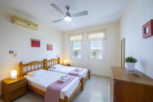 1 Schlafzimmer mit 2 Betten, einem Schreibtisch und einem Fenster in der Unterkunft Protaras Villa Marilia in Protaras