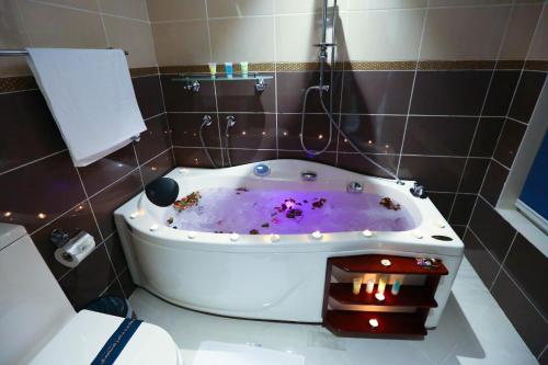 Bait Aldiyafah Hotel Apartments في جدة: حمام مع حوض استحمام مع صبغ أرجواني