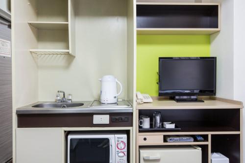 a small kitchen with a microwave and a tv at HOTEL MYSTAYS Ueno Inaricho in Tokyo