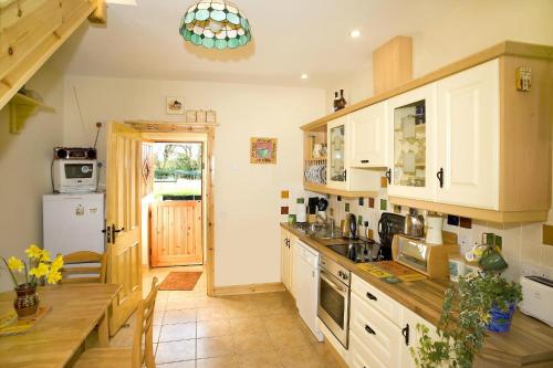 a kitchen with white cabinets and a table in it at Riverfield Lodge in Athboy