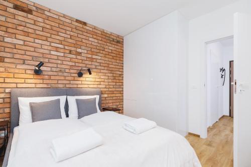 1 Schlafzimmer mit 2 weißen Betten und Ziegelwand in der Unterkunft Apartments Supernova near Tauron Arena by Renters in Krakau