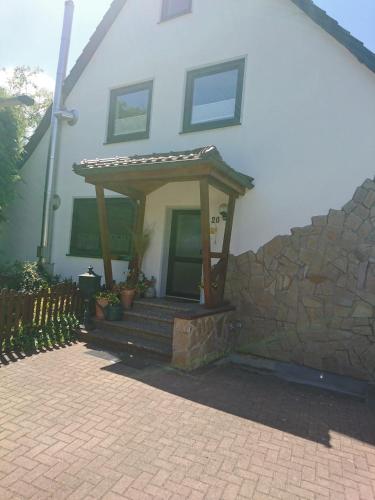 a house with a porch with a stone wall at Ferienwohnung Reichelt in Neuwinsen